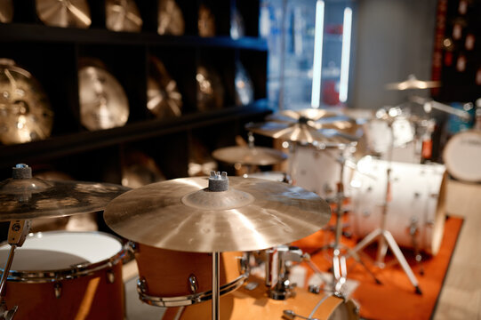 Selective view on drum set and several golden cymbal plates in music shop