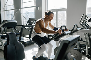 Fototapeta na wymiar Healthy smiling sportsman using elliptical machine at gym fitness center