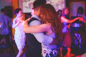 Foto auf Acrylglas Tanzschule Couples dancing traditional latin argentinian dance milonga in the ballroom, tango salsa bachata kizomba lesson in the red and purple lights, dance school class festival