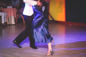 Fototapeta premium Couples dancing traditional latin argentinian dance milonga in the ballroom, tango salsa bachata kizomba lesson in the red and purple lights, dance school class festival