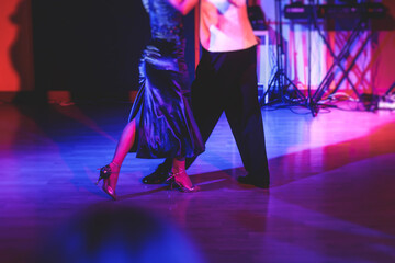 Couples dancing traditional latin argentinian dance milonga in the ballroom, tango salsa bachata kizomba lesson in the red and purple lights, dance school class festival