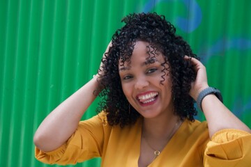 dominican woman in green wall with smile and yellow dress