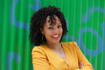 dominican woman in green wall with smile and yellow dress - obrazy, fototapety, plakaty