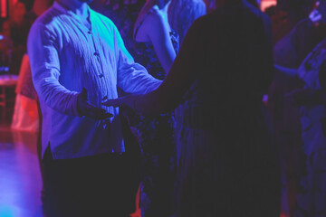 Couples dancing traditional latin argentinian dance milonga in the ballroom, tango salsa bachata kizomba lesson in the red and purple lights, dance school class festival