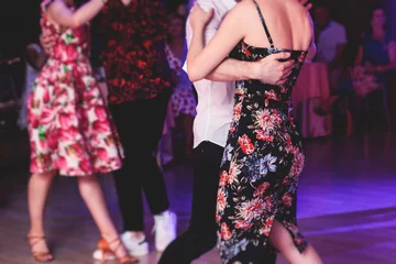 Photo sur Plexiglas École de danse Couples dancing traditional latin argentinian dance milonga in the ballroom, tango salsa bachata kizomba lesson in the red and purple lights, dance school class festival