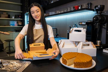 Young cafe employee preparing pastry for takeaway
