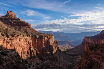Fototapeta na wymiar Panoramic aerial view from Bright Angel hiking trail at South Rim of Grand Canyon National Park, Arizona, USA. Vista after sunrise in summer. Colorado River weaving through valleys and rugged terrain