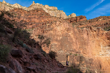Woman hiking along Bright Angel trail with panoramic aerial overlook of South Rim of Grand Canyon National Park, Arizona, USA, America. View on massiv cliffs, rock formations and steep stone walls