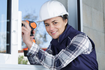 female construction worker drilling a window