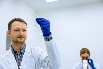 Male scientist analyzes liquid female researcherworking with microscope investigating medical sample