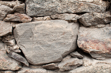 A wall of irregularly laid stones with mortar and cement