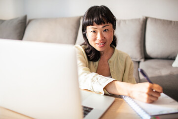 Young Japanese Woman working on a laptop in the kitchen