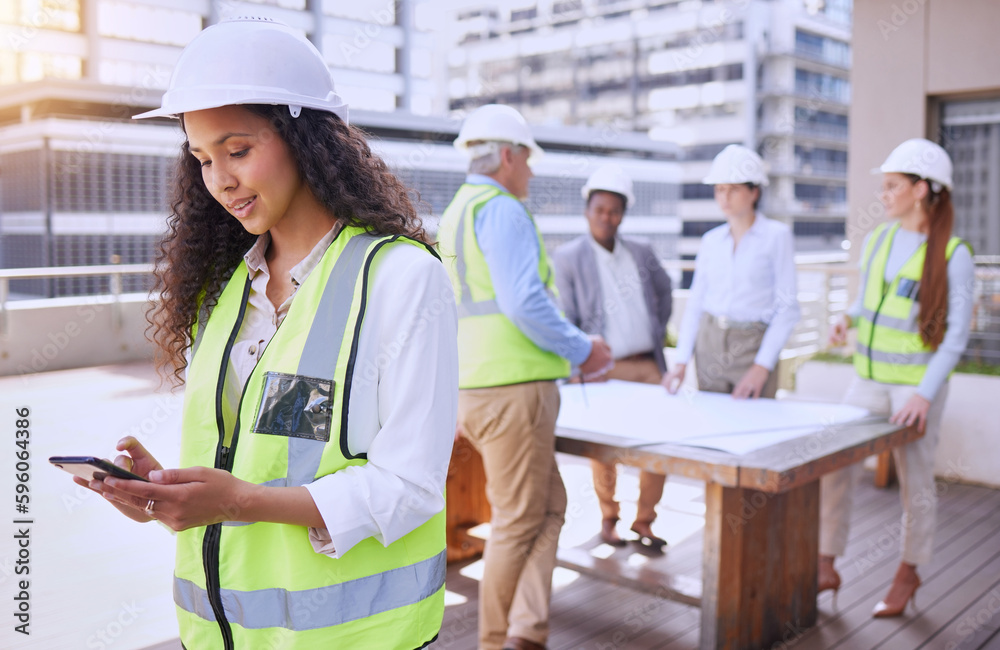 Poster checking site updates. an attractive young female construction worker using a cellphone while standi