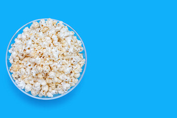 Popcorn in a large glass bowl on a blue background with a top view. Crispy classic popcorn snack for watching movies and series. Delicious light snack for watching TV. Free space for text