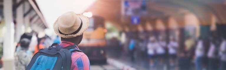 African man traveling with backpack in train, backpack and hat at train station with travelers, travel concept. Travel man walking at train station