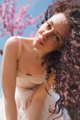 A young girl among beautiful peach flowers in full bloom. Pink peach blossom garden. Springtime.