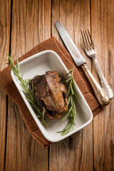 roasted pigeon with herbs over wood background