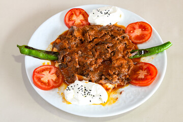 Traditional turkish iskender kebab in copper plate with yogurt, grilled tomatoes and fresh vegetables.