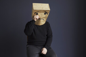 Sad man with a bag on his head, with a drawn crying emoticon. - obrazy, fototapety, plakaty