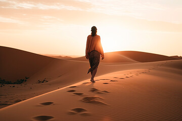 Fototapeta na wymiar A women with summer clothes Walking alone on the desert at sunset