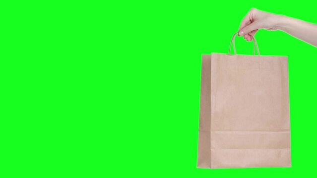 Hand holding showing brown package bag isolation, green screen background