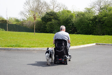 Walking the dog disabled style, man on a mobility scooter enjoys the freedom to walk his spaniel dog in the countryside despite his disability.