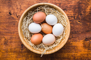 Whole chicken eggs in bowl on wooden table. Top view.