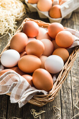 Whole chicken eggs in basket on wooden table.