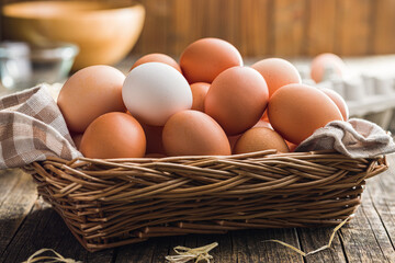 Whole chicken eggs in basket on wooden table.