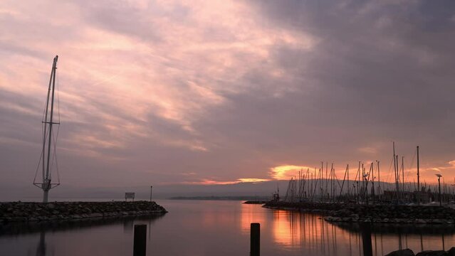 Sunset over lake. Landscape of lake Geneva, mountain and Ouchy waterfront statue. Port of Ouchy, Lausanne, Vaud Canton, Switzerland. Time lapse from day to night.