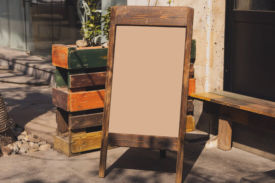 Blackboard in front of restaurant entrance. Mock up menu blank board sign stand near shop or cafe restaurant. Street magnetic sidewalk chalkboard - Powered by Adobe