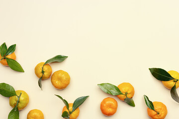 Whole orange yellow tangerines with green leaves on pastel beige background, copyspace. Citrus fruits mandarines as minimal food frame background, empty space, above view, still life photo
