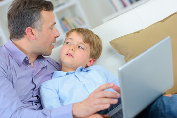 Man and child at home, holding laptop