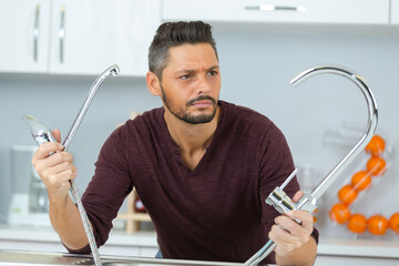 confused man fixing water tap in a bathroom using spanner