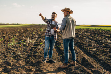 Two farmers standing in the field and using a digital tablet