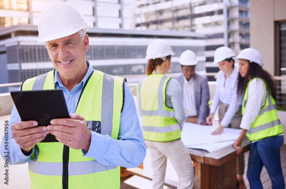 Poster running the entire operation on his tablet. a handsome mature male construction worker using a table