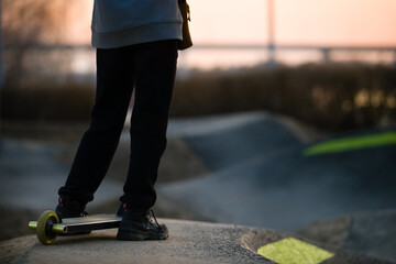 Closeup, the boy's legs with a stunt scooter in a skate park make jumps and tricks. Extreme jumping on a scooter. The concept of a healthy lifestyle and sports recreation