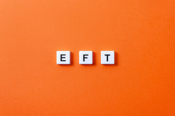 Letters EFT from plastic blocks on orange background. Minimal concept of Emotional Freedom...