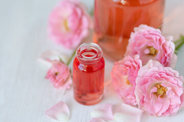 Concept of perfume with pure natural organic rose ingredient, essential oils. Glass bottles with flower herbal extract and elixir. Perfumery cosmetic toilet water fragrance, cream, skin care product