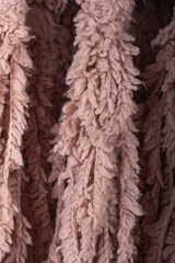 Closeup fringe on soft knit throw blanket is beige. Decor, design, decoration, texture.
