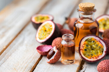 Glass bottles with pure organic essential litchi and passion fruit oil on wooden background. Concept of natural ingredients for beauty treatment, skin care, massage. Exotic fruits extract and essence