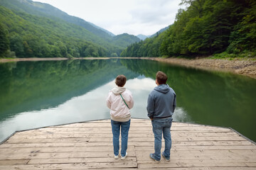 Tourists admiring of breathtaking landscape of mountain lake Biogradsko in alps of Montenegro on spring day. Stunning view of mountains and valleys in national park Biogradska Gora.
