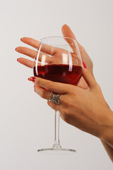 Woman's hand holding a glass of red wine on a white background