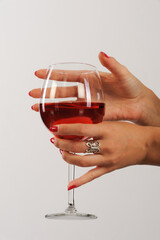 Woman's hands with red manicure holding a glass of red wine