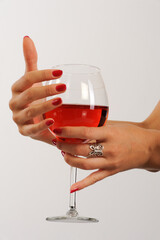 Woman's hands with red manicure holding glass of red wine on white background