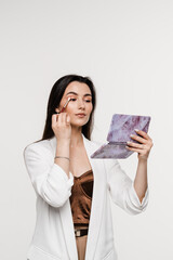 Girl does herself makeup with brush using color palette to draw shadows on her eyes. Professional cosmetics for make-up artist for perfect skin.