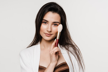 Professional make-up artist with makeup brushe on white background. Attractive girl is holding eye shadow brushes and smiling.