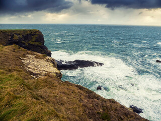Rough stone coastline, Cliffs of Kilkee county Clare, Ireland. Wild Irish nature landscape. Popular travel area with stunning nature scenery. Dramatic sky and powerful ocean waves.