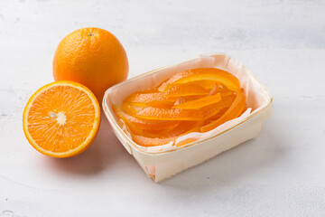 Wicker birch basket with fresh juicy candied oranges with fresh juicy orange on a light gray background