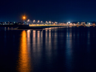 Fototapeta na wymiar Light on a pier reflecting in water. Galway city, Ireland. Night shot. Town illumination.
